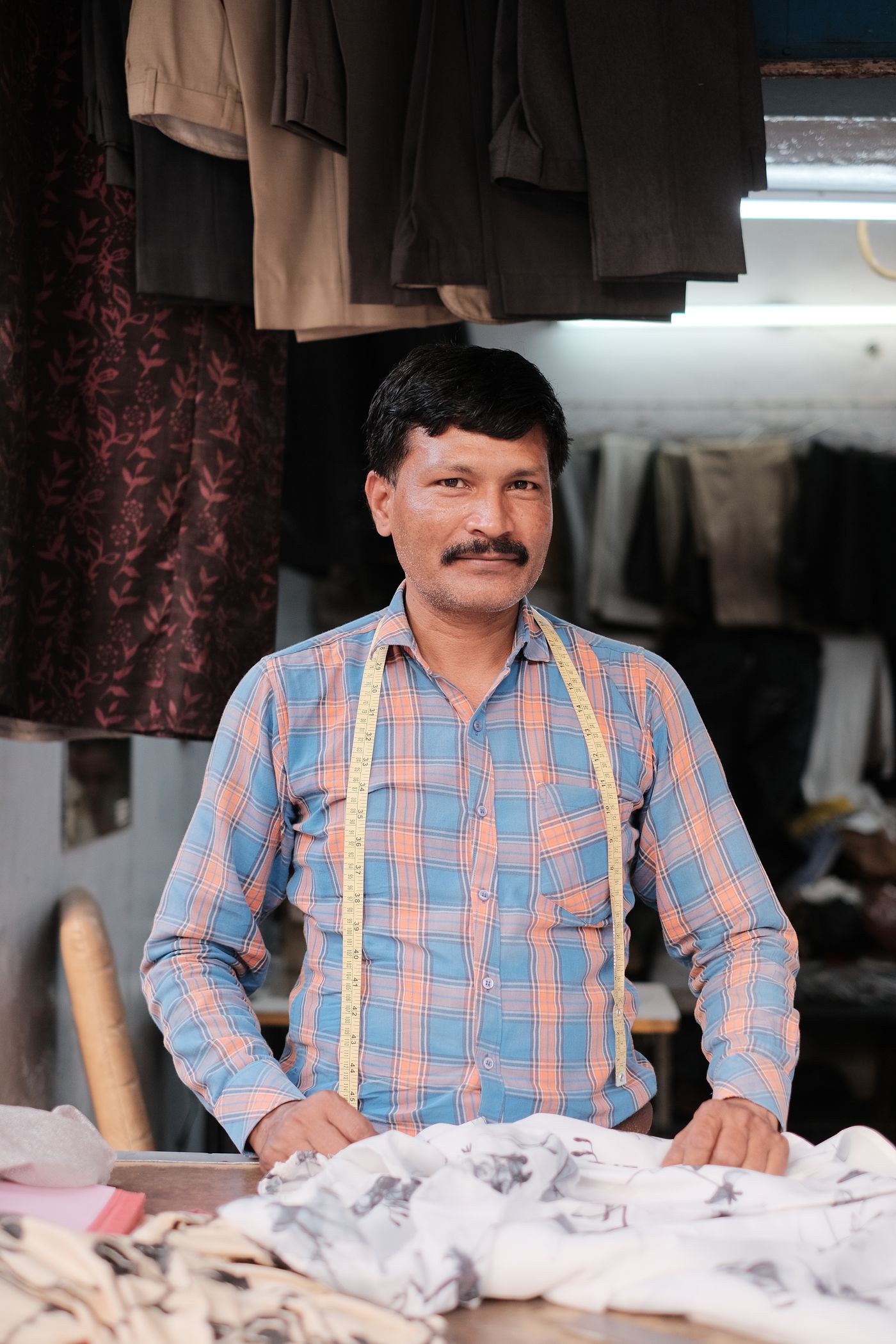 Indian tailor standing at his workshop counter
