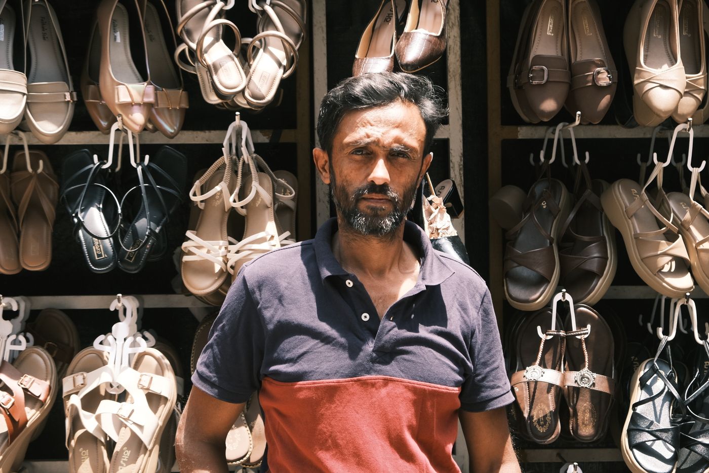 Indian shopkeeper in front of his footwear stall