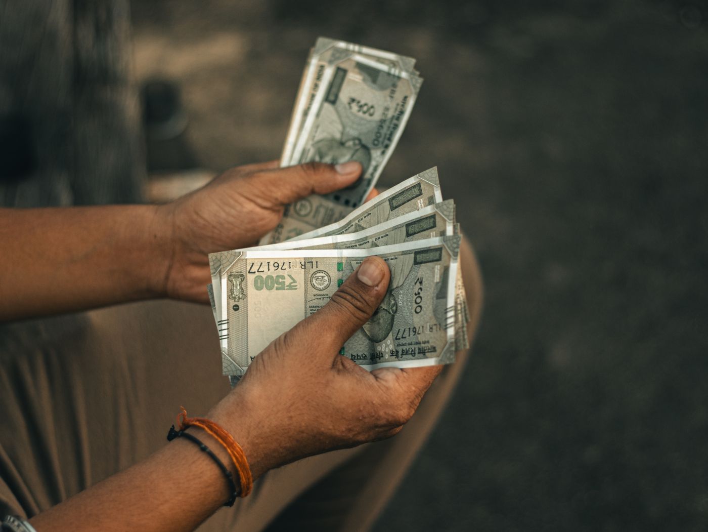 Hands counting a bundle of 500-rupee notes